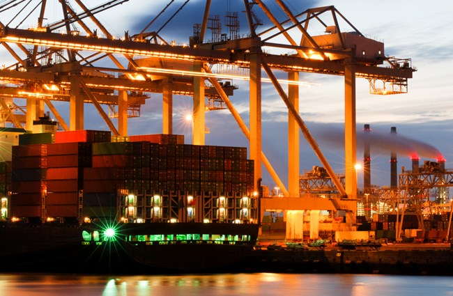 An image of container ships docked in a port at night