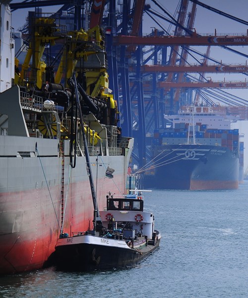 A tug boat alongside a larger vessel in a harbour