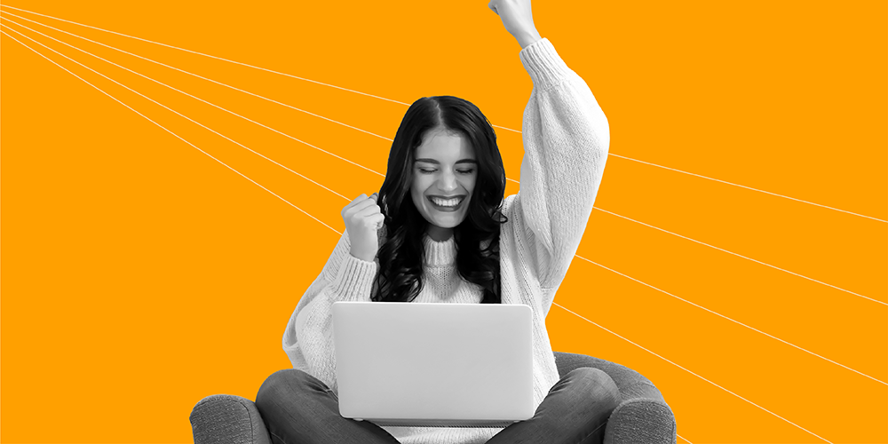 young woman sitting cross legged in armchair with laptop celebrating the best financial decision she made in her 20s