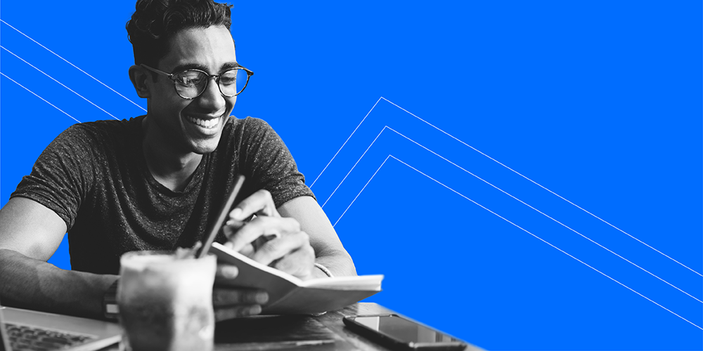 young man with glasses working on computer with coffee