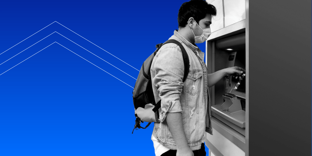 A man wearing a face mask and a backpack pushing buttons at an ATM