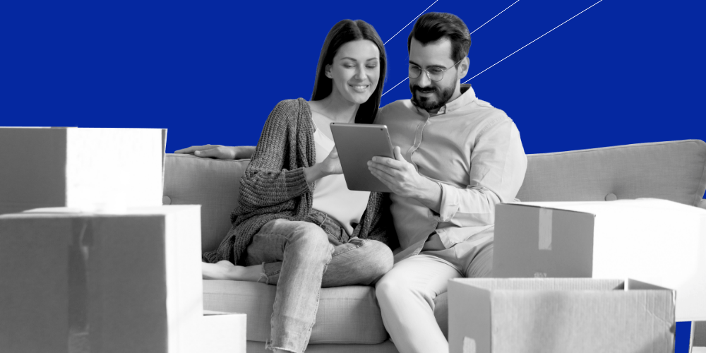 A male-female couple sitting closely on a coach huddled over an ipad together